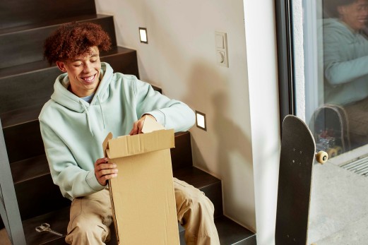 teenager smiling and opening a parcel