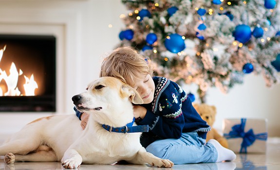 bambino e cane davanti all'albero di Natale