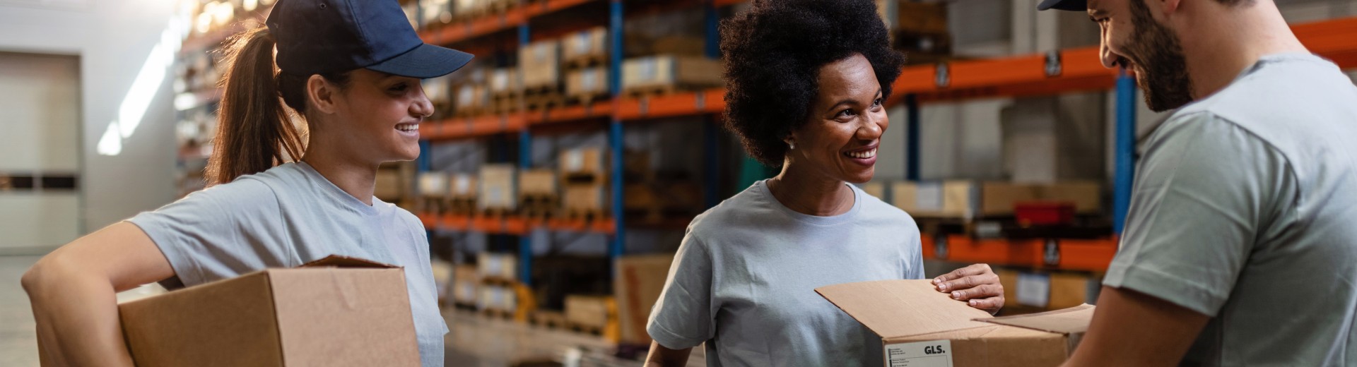 Workers handling boxes and discussing tasks in a warehouse.